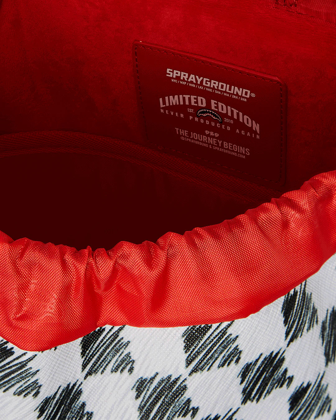 Black and white checkered backpack with a shark logo on a white background by sprayground