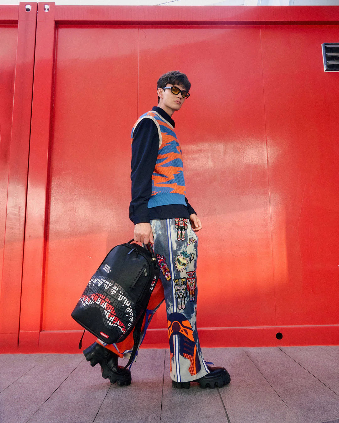 Black backpack with colorful branding on a white background by sprayground