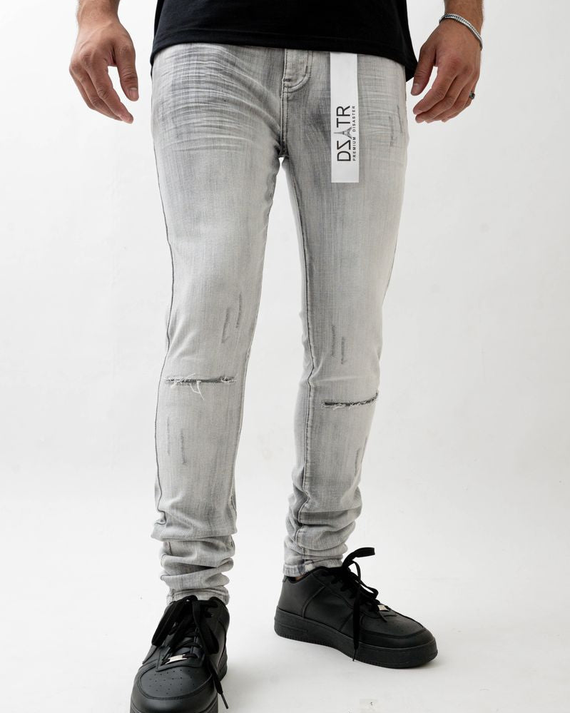 Person wearing light gray distressed jeans with a brand label on a white background