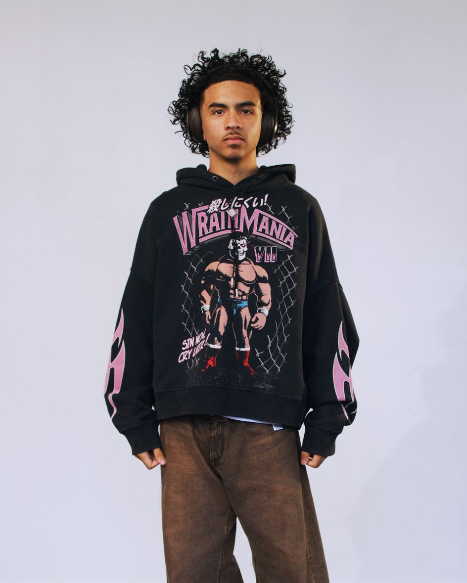 Person wearing a black hoodie with pink and white graphics on a plain background