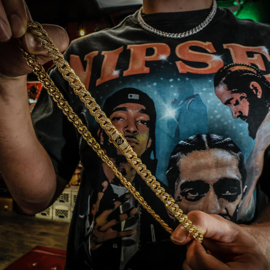 Person wearing a graphic t-shirt with faces and holding a gold cuban link chain.