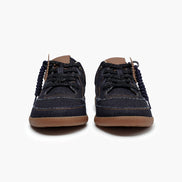 Pair of dark blue denim shoes with brown soles on a white background