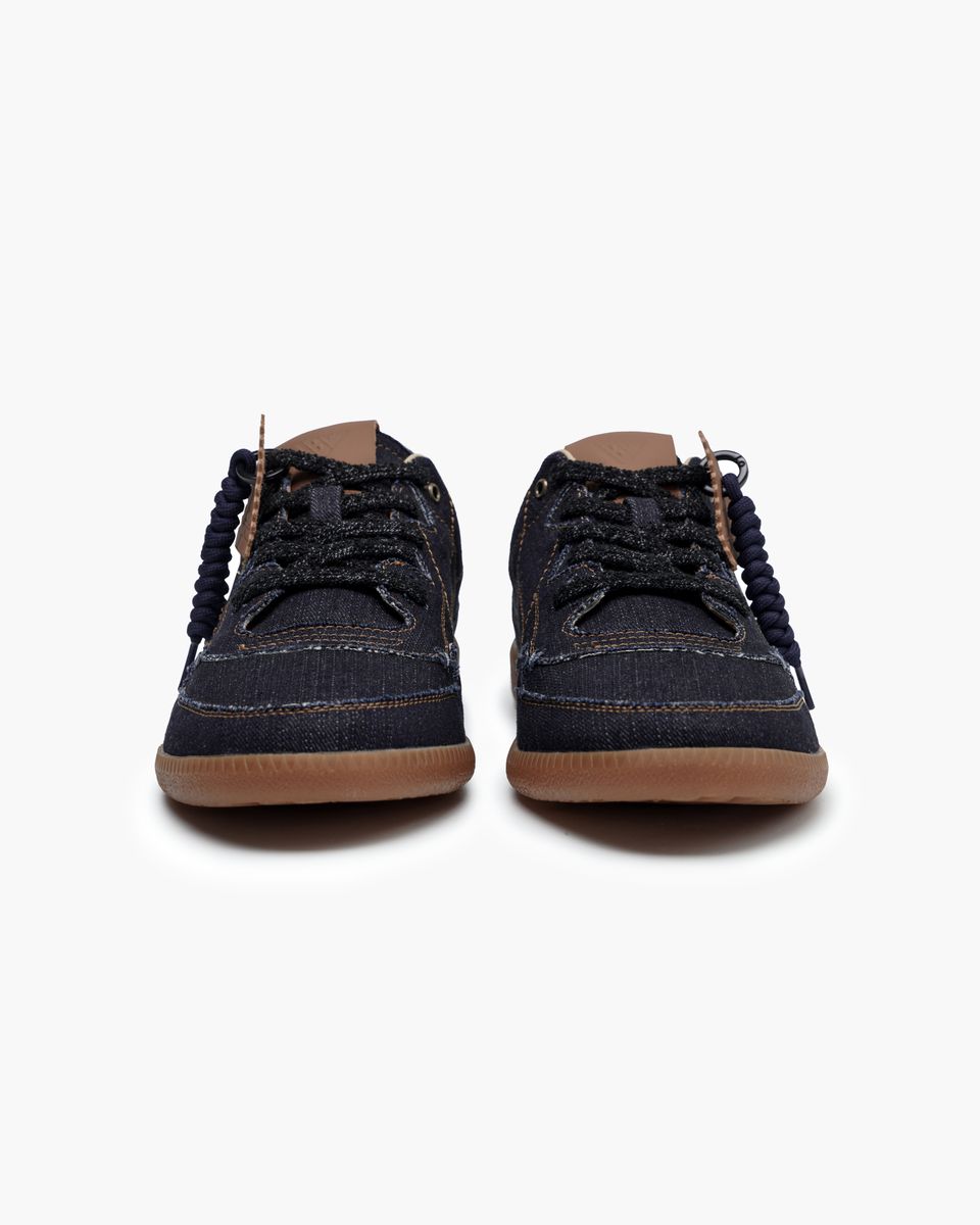 Pair of dark blue denim shoes with brown soles on a white background