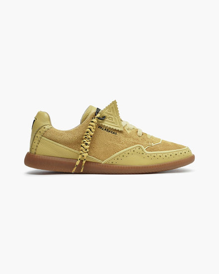 Yellow sneaker with brown sole on a white background