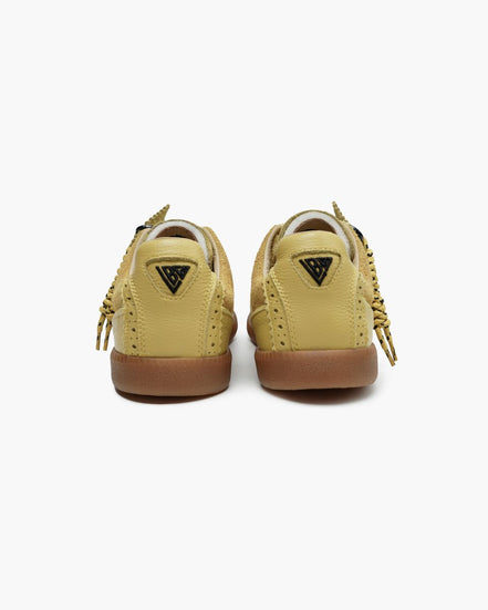 Pair of yellow beige sneakers with brown soles on a white background