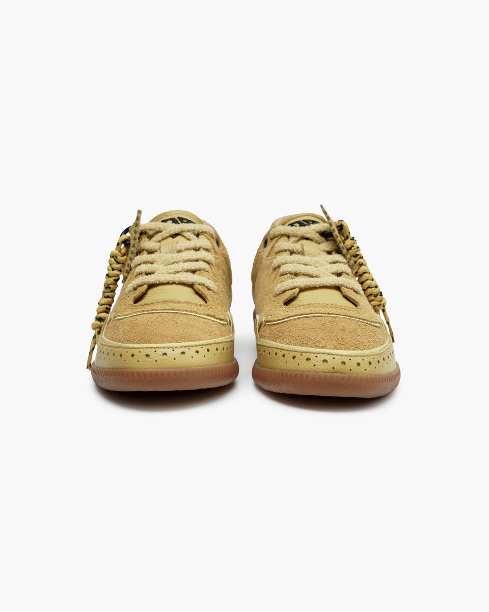 Pair of yellow tan sneakers on a white background