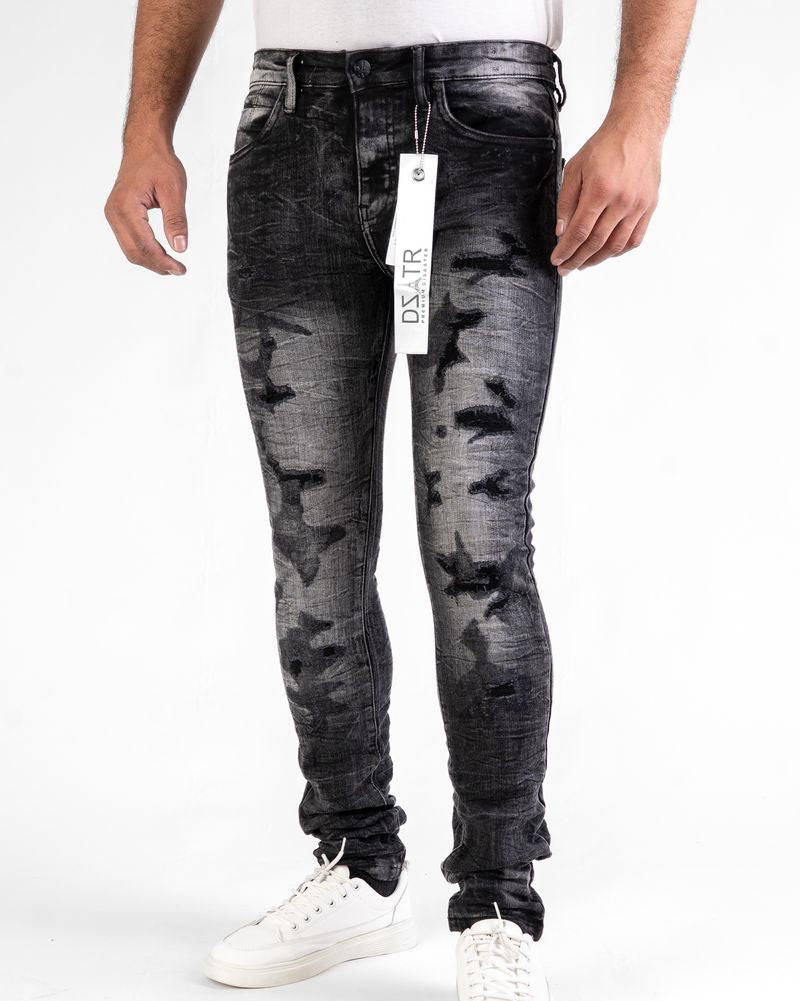 Person wearing black distressed jeans with a visible brand tag on a white background