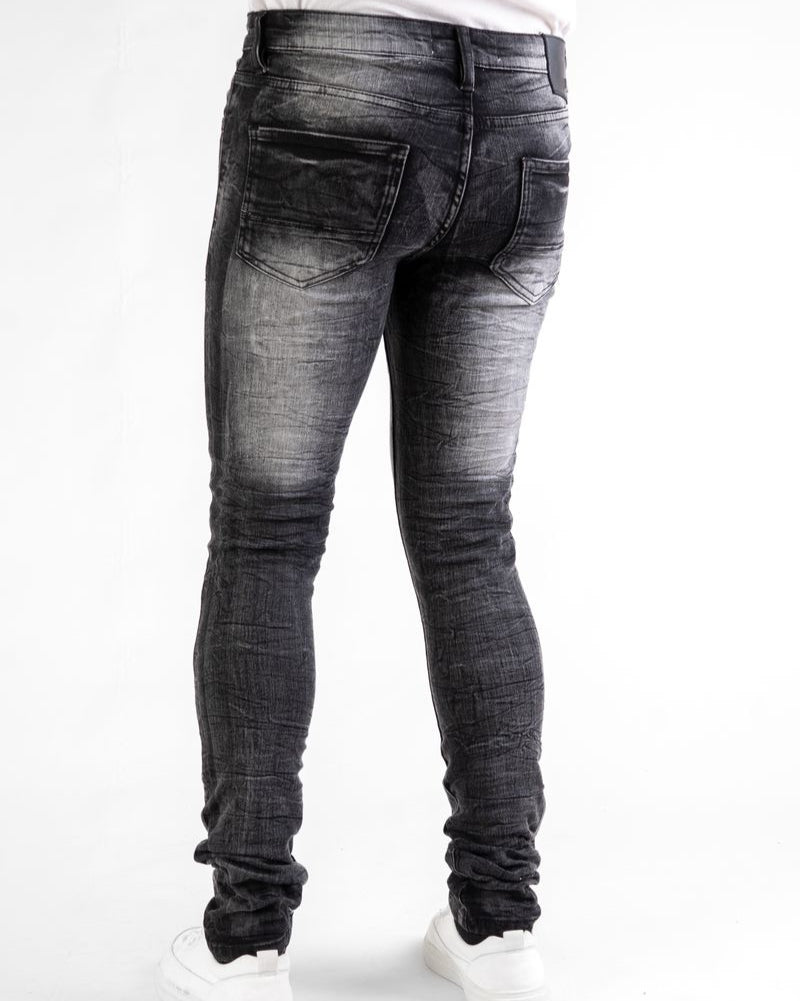 Black distressed jeans worn by a person on a white background