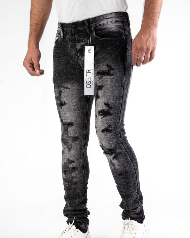 Person wearing black distressed jeans with a visible brand tag on a white background