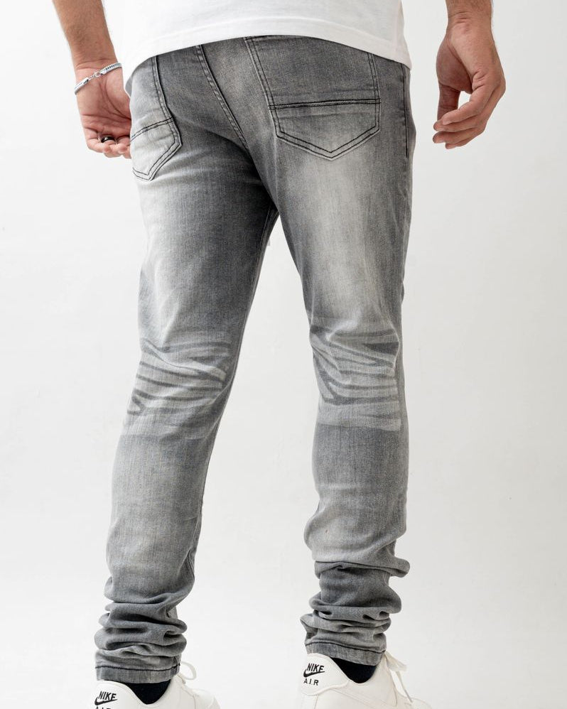 Person wearing gray jeans and white sneakers on a white background