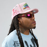 Person wearing a pink cap and sunglasses with a light gray background
