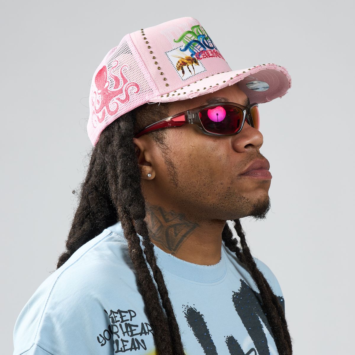 Person wearing a pink cap and sunglasses with a light gray background