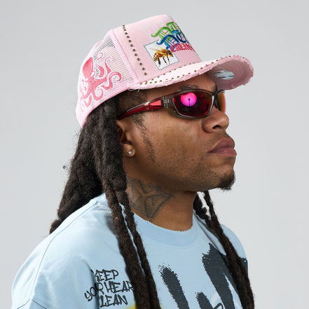 Person wearing a pink cap and sunglasses with a light gray background