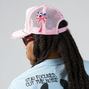 Person wearing a pink cap with palm tree design and sunglasses, facing away from the camera.