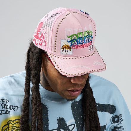 Person wearing a pink cap with colorful text and graphics on a gray background