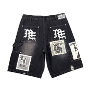 Black denim shorts with newspaper print and branding on a white background