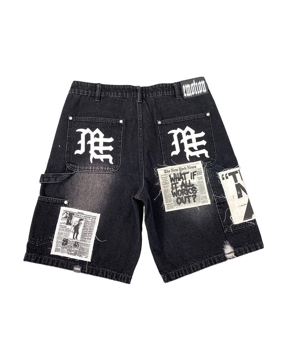 Black denim shorts with newspaper print and branding on a white background