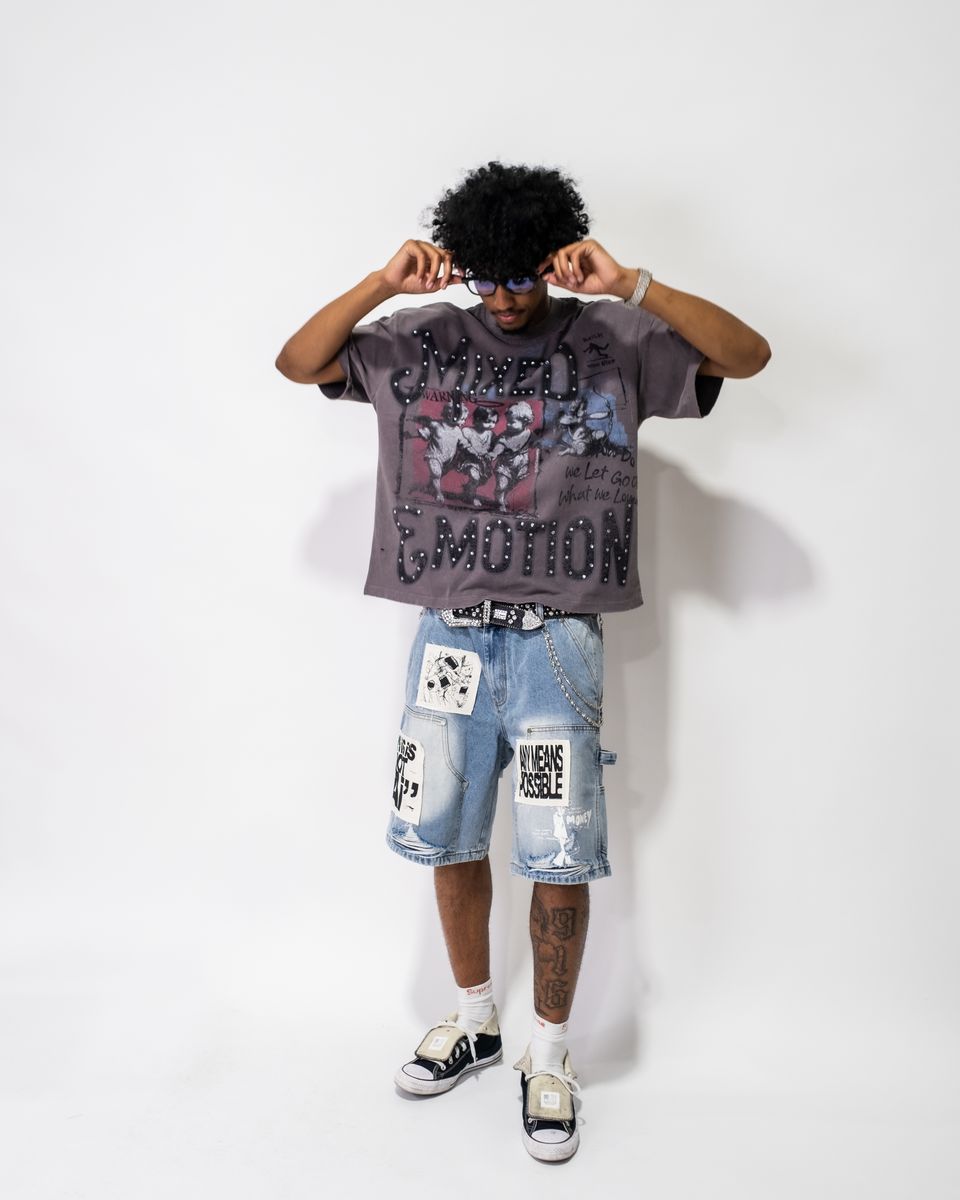 Person wearing a graphic t-shirt and denim shorts on a white background