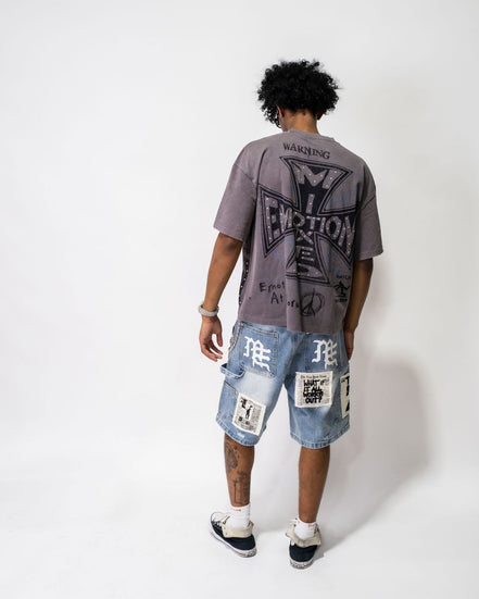 Person wearing a graphic t-shirt and patchwork shorts on a white background