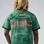 Person wearing a green t-shirt with text and graphics on the back, standing against a plain background.