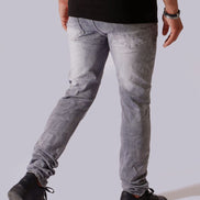 A person shown from the back wearing slim-fit light gray washed jeans, a black t-shirt, and black sneakers against a plain light gray studio background.