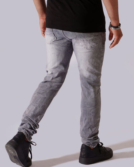 A person shown from the back wearing slim-fit light gray washed jeans, a black t-shirt, and black sneakers against a plain light gray studio background.