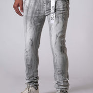 Person wearing gray distressed jeans with a visible brand tag on a plain background