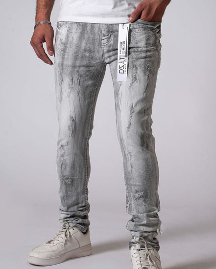 Person wearing gray distressed jeans with a visible brand tag on a plain background