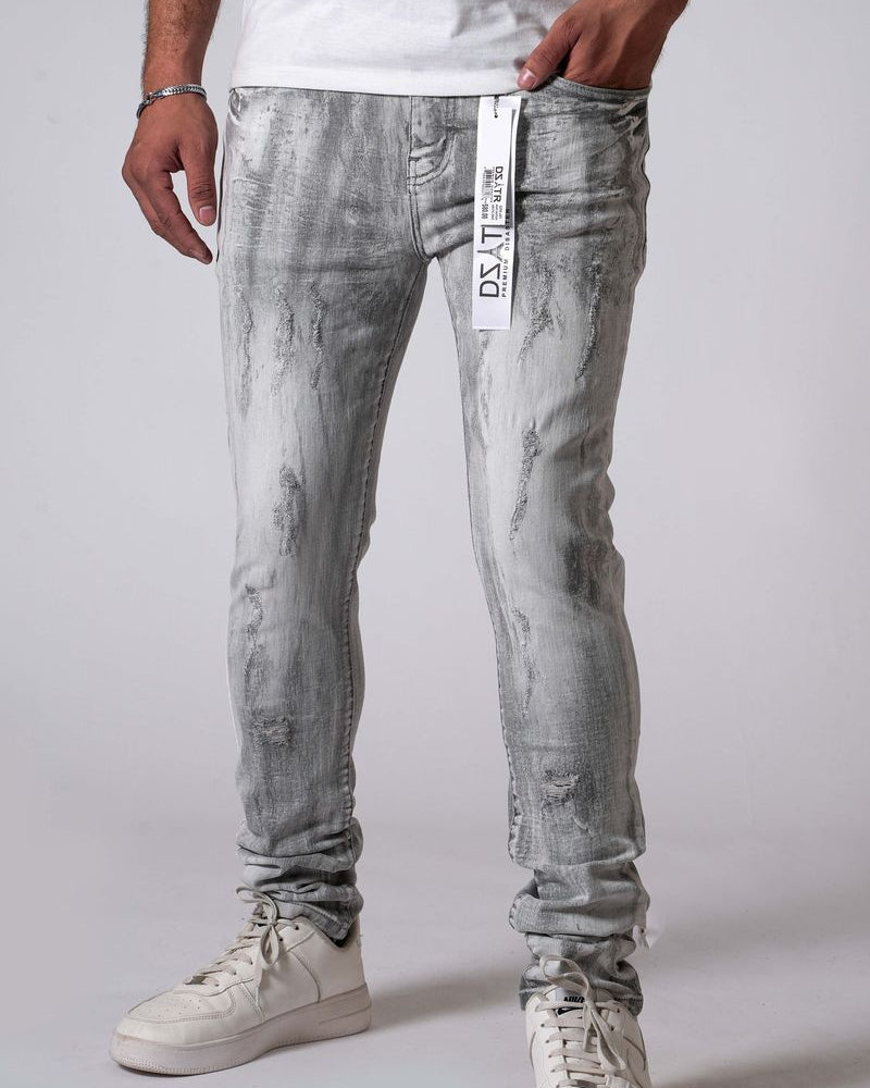 Person wearing gray distressed jeans with a visible brand tag on a plain background