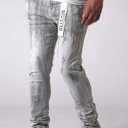 Person wearing light gray distressed jeans with a white logo on a plain background