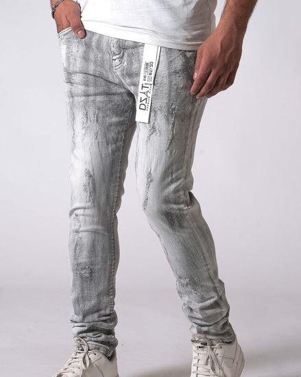 Person wearing light gray distressed jeans with a white logo on a plain background