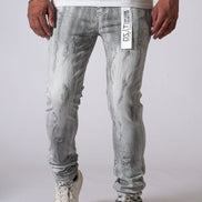 Person wearing light gray distressed jeans and white sneakers on a plain background