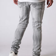 Person wearing light gray jeans and white sneakers on a plain background