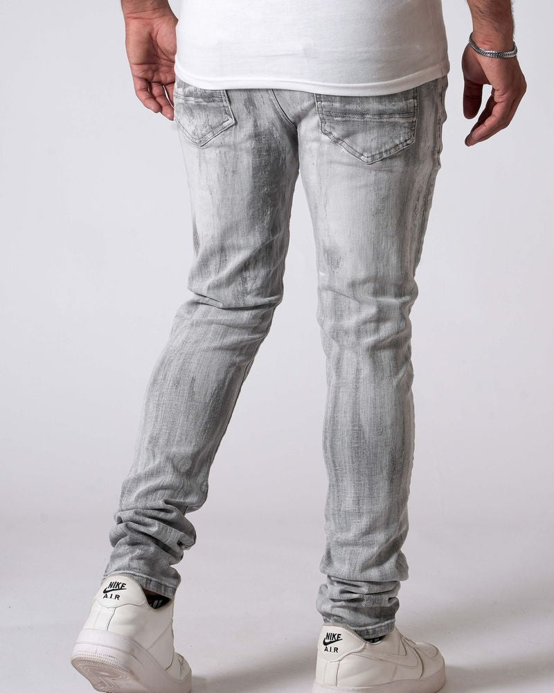Person wearing light gray jeans and white sneakers on a plain background