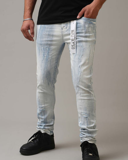 Person wearing light blue distressed jeans with a brand label on a neutral background