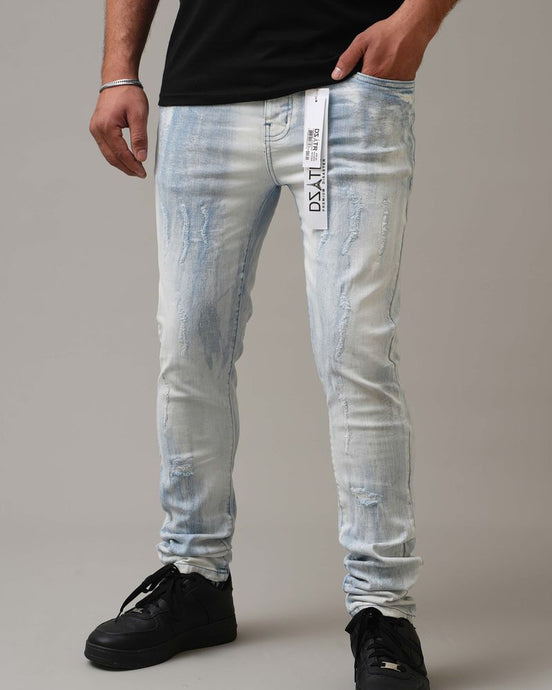 Person wearing light blue distressed jeans with a brand label on a neutral background