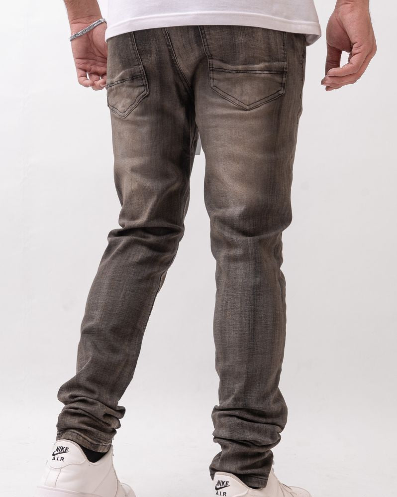 Person wearing dark gray jeans and white sneakers on a white background