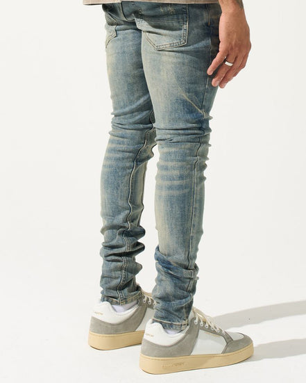 Person wearing light blue jeans and gray sneakers on a white background