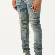 Person wearing light blue distressed jeans and gray sneakers on a white background