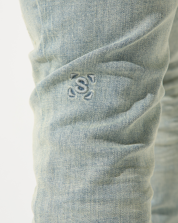 Close-up of light blue denim jeans with a brand logo on the pocket.