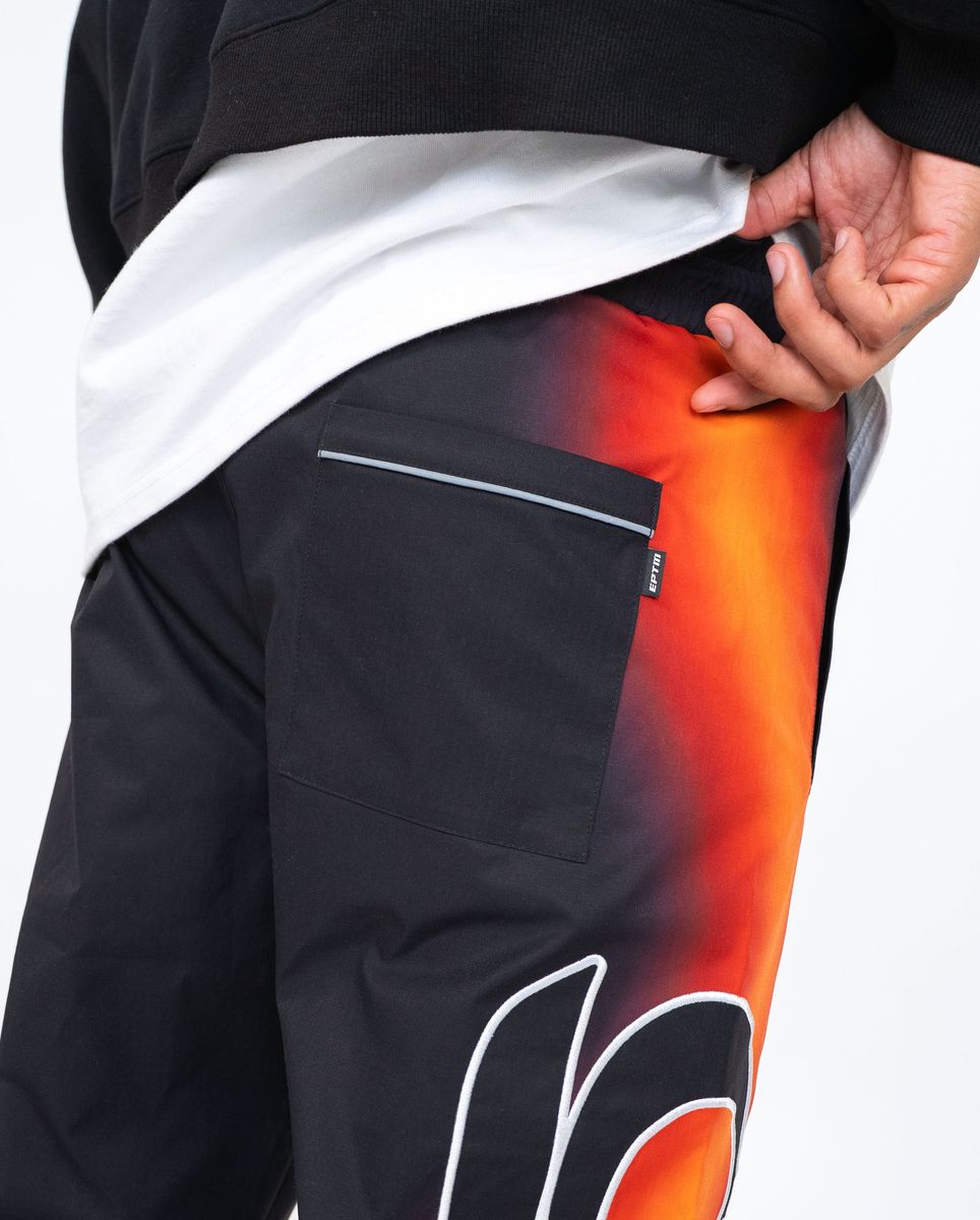 Black pants with a colorful design on the leg, held by a person.