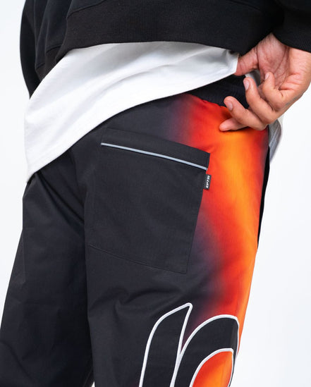Black pants with a colorful design on the leg, held by a person.