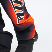 Close-up of a person wearing black boots and colorful pants with flame design on a white background
