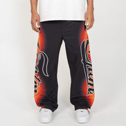 Person wearing black sweatpants with red and orange designs on a white background