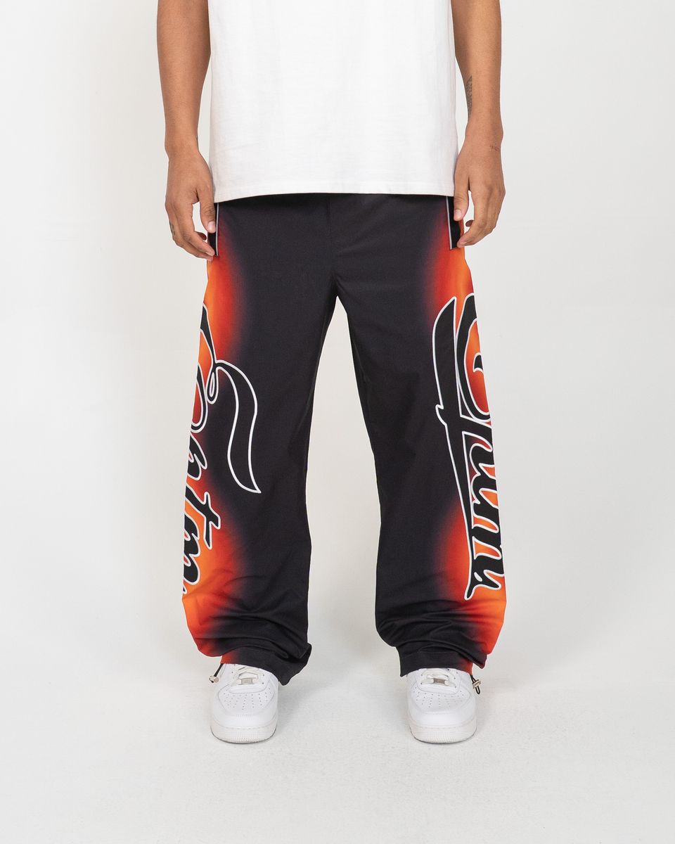Person wearing black sweatpants with red and orange designs on a white background