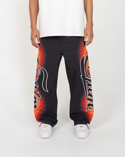 Person wearing black sweatpants with red and orange designs on a white background