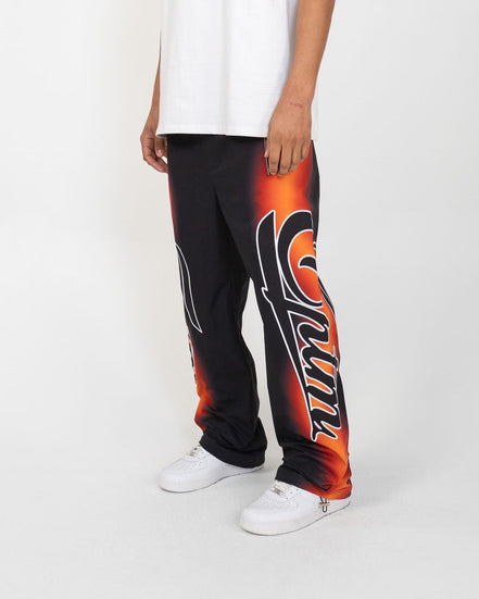 Person wearing black and orange pants with a logo on a white background