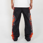 Black pants with red and orange designs worn by a person on a white background