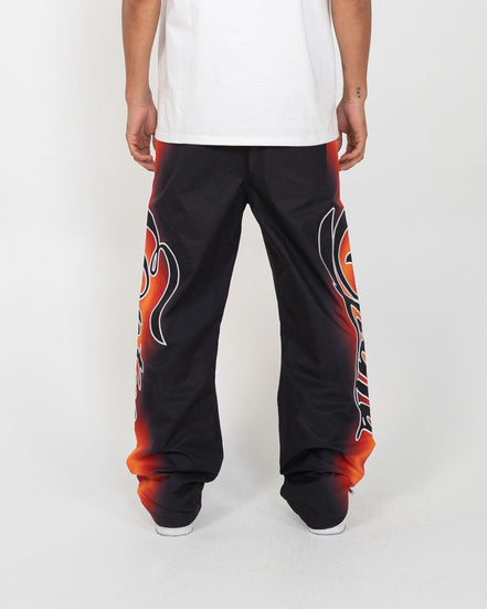 Black pants with red and orange designs worn by a person on a white background