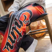 Person wearing a colorful jacket with a prominent logo, sitting on a chair.
